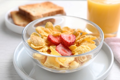 Tasty cornflakes with milk and strawberries on white wooden table, closeup. Healthy breakfast