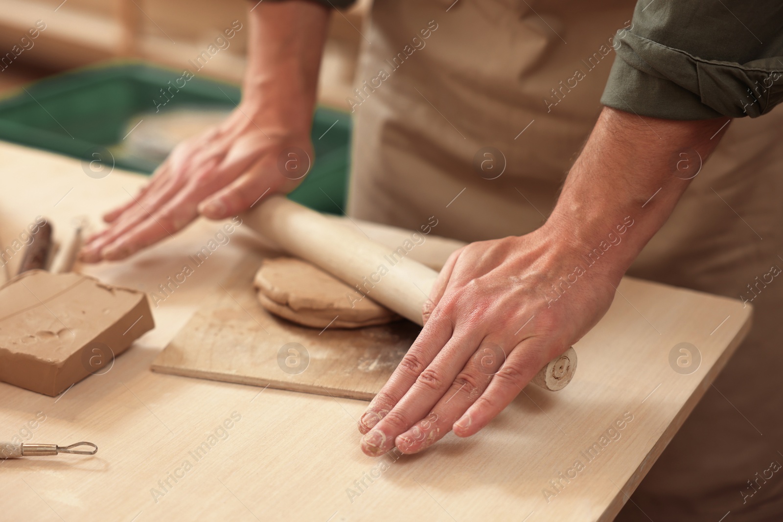 Photo of Man crafting with clay at table indoors, closeup