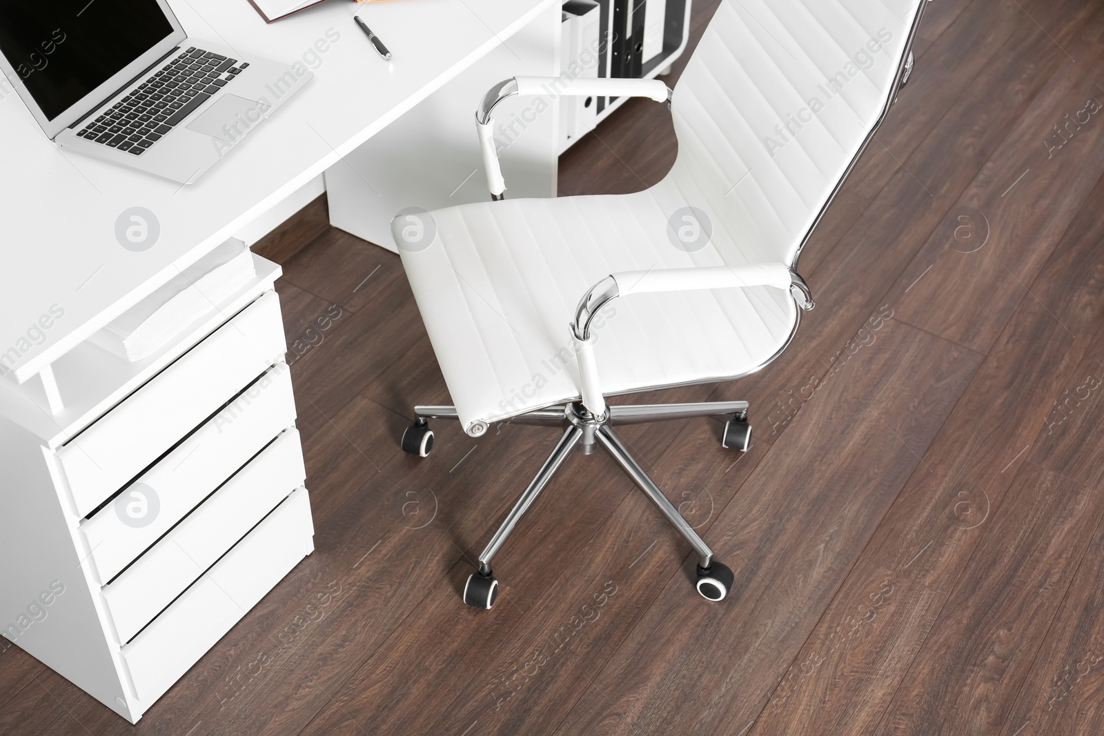 Photo of Comfortable rolling chair near table with laptop in modern office