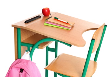 Wooden school desk with stationery, backpack and apple on white background