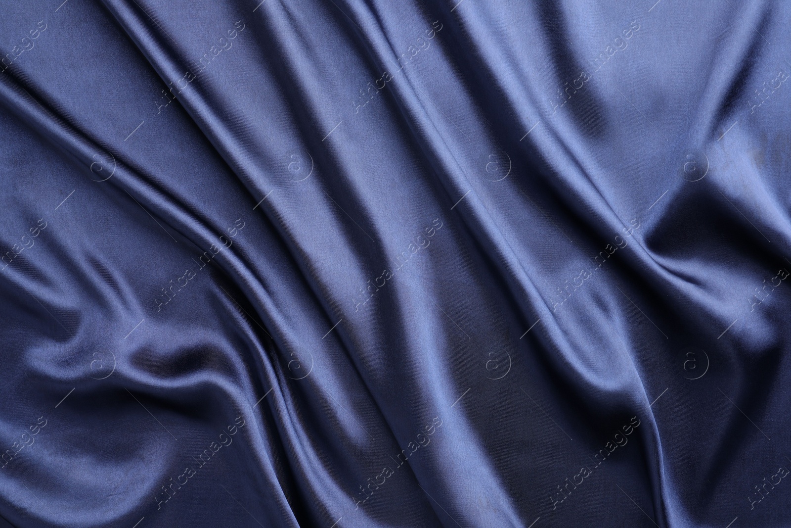 Photo of Crumpled dark blue silk fabric as background, top view