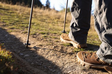 Photo of Hiker with trekking poles walking outdoors on sunny day, closeup