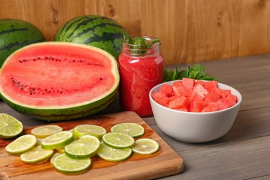 Photo of Tasty watermelon drink with lime and fresh ingredients on wooden table