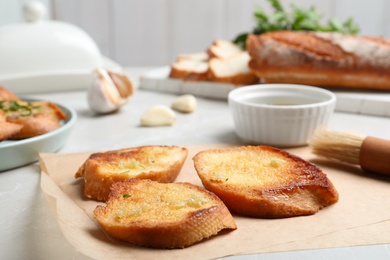 Photo of Slices of delicious toasted bread with garlic on table