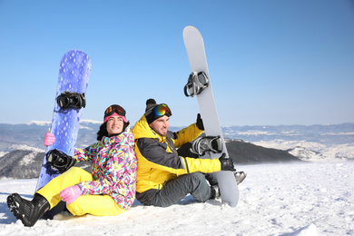 Photo of Couple with snowboards on hill. Winter vacation