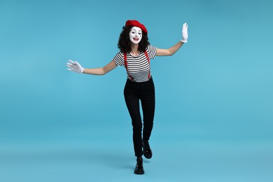 Funny mime with beret posing on light blue background