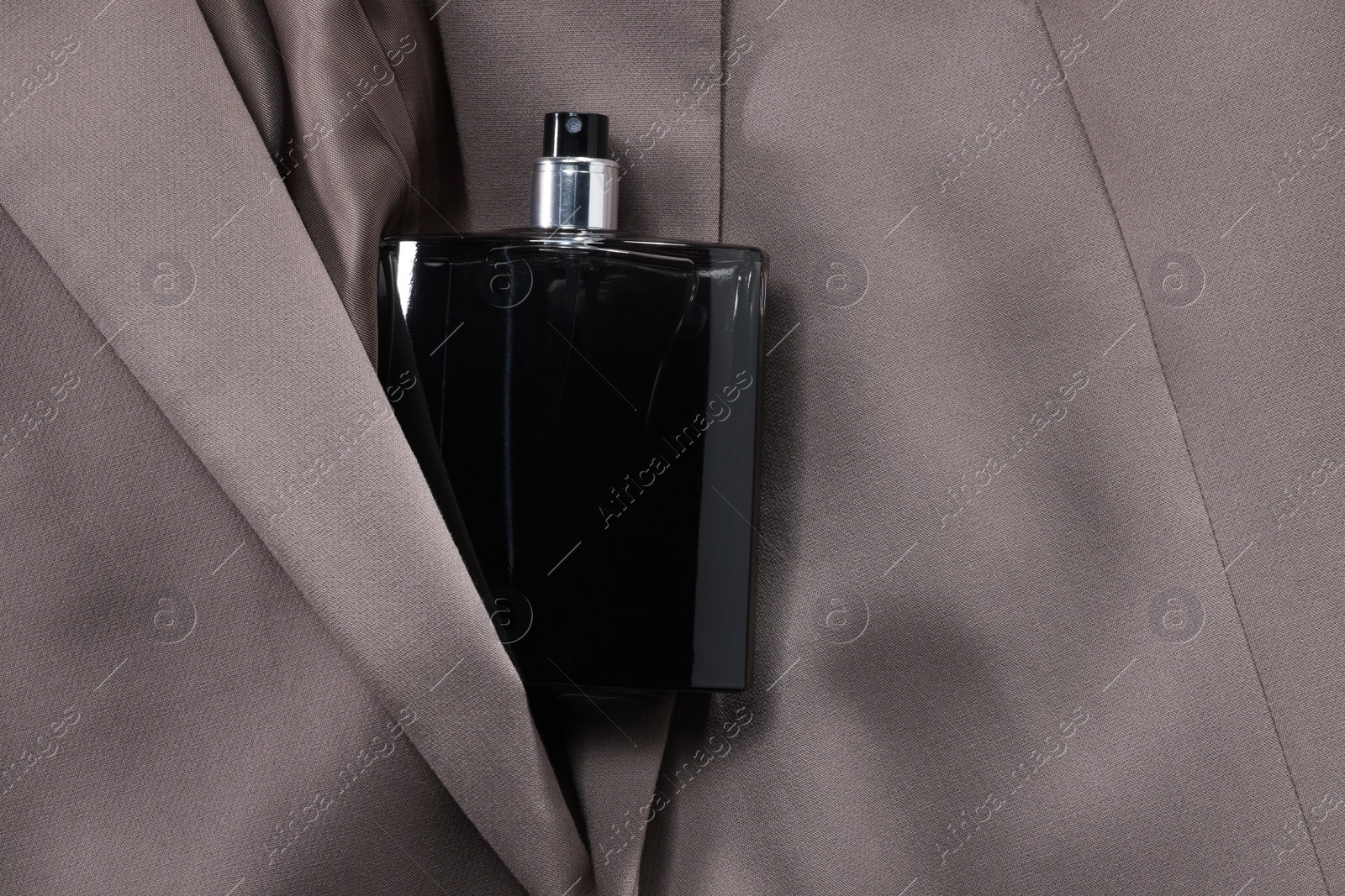 Photo of Luxury men's perfume in bottle on beige jacket, top view. Space for text