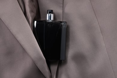 Photo of Luxury men's perfume in bottle on beige jacket, top view. Space for text