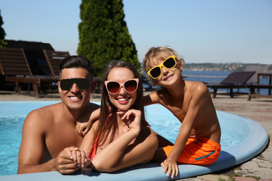 Photo of Happy family in outdoor swimming pool on sunny summer day