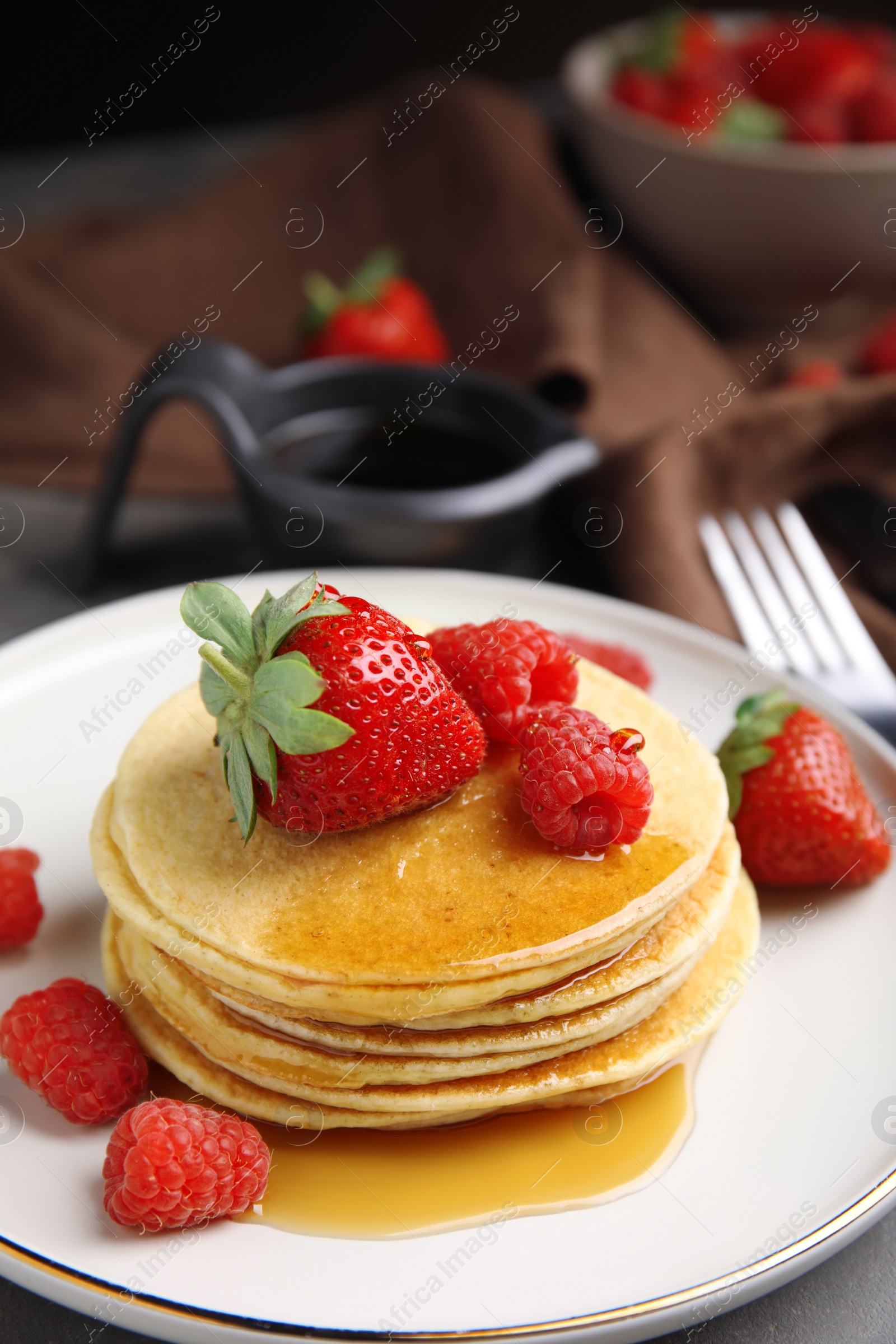 Photo of Tasty pancakes with fresh berries and honey on plate, closeup