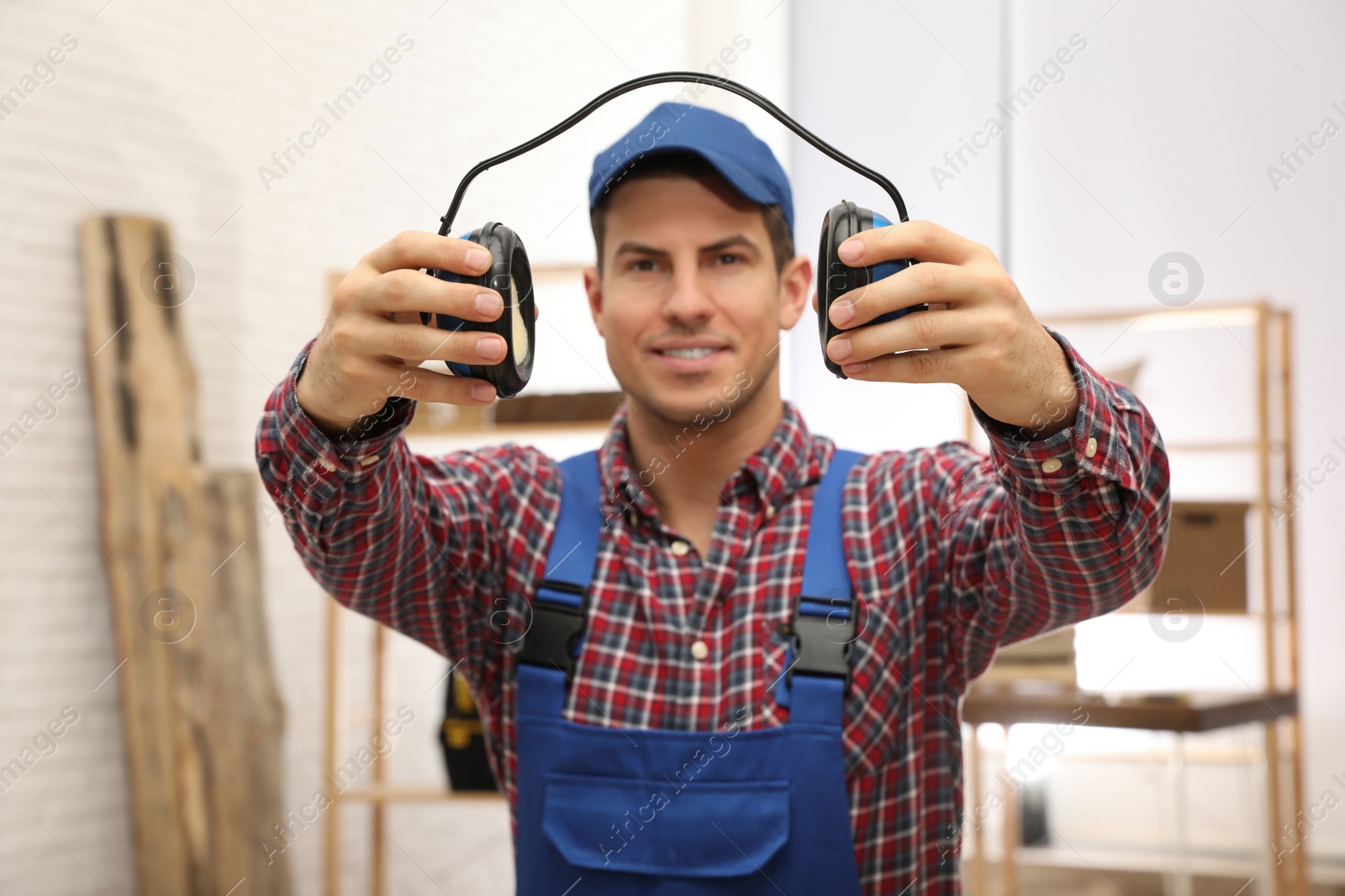 Photo of Worker holding safety headphones indoors, focus on hands. Hearing protection device