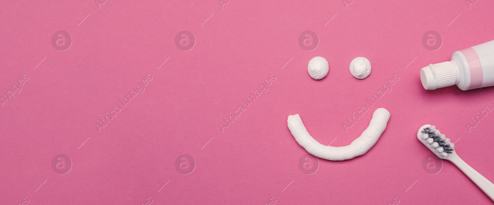 Image of Smiling face made of toothpaste, brush and tube on pink background, flat lay with space for text. Banner design