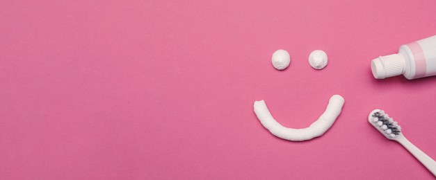 Image of Smiling face made of toothpaste, brush and tube on pink background, flat lay with space for text. Banner design