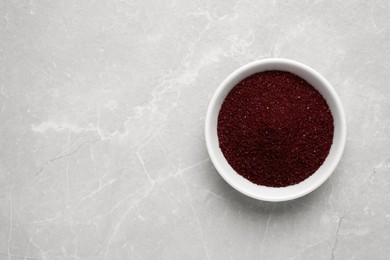 Bowl with dark red food coloring on light grey marble table, top view. Space for text