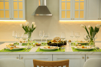 Photo of Festive Easter table setting with floral decor in kitchen