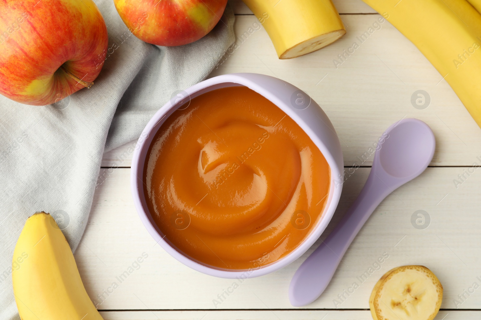 Photo of Healthy baby food in bowl and fresh fruits on white wooden table, flat lay