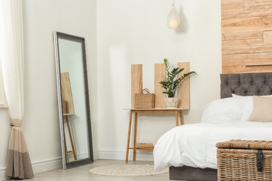 Photo of Stylish wooden table, mirror and bed in modern room interior