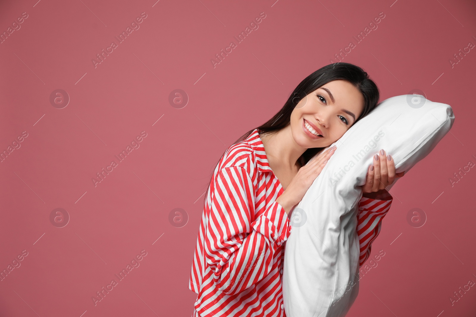 Photo of Beautiful Asian woman with pillow on dusty rose background, space for text. Bedtime