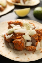 Photo of Delicious taco with vegetables, meat and lime on table, closeup