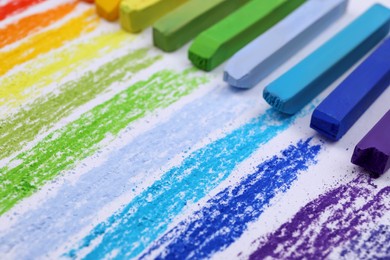 Photo of Colorful pastel chalks on white background, closeup. Drawing materials