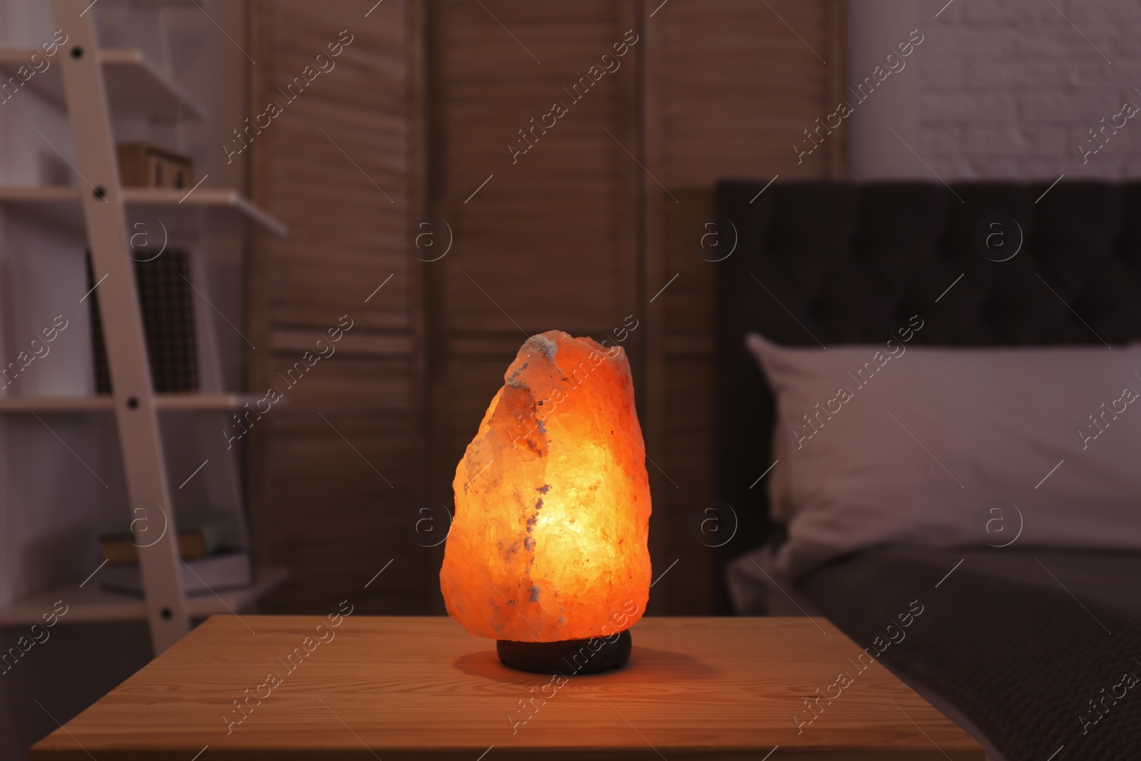 Photo of Himalayan salt lamp on table in dark room