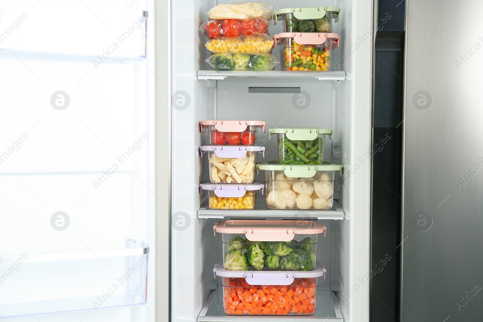 Photo of Containers with different frozen vegetables in refrigerator