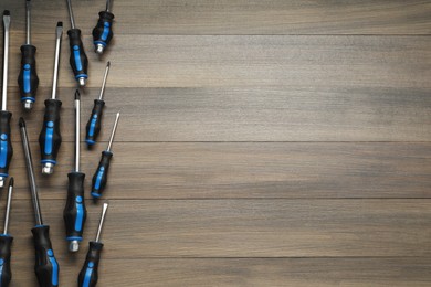 Set of screwdrivers on wooden table, flat lay. Space for text