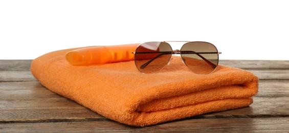 Photo of Beach towel, sunglasses and sun protection product on wooden surface against white background