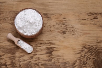 Photo of Bowl and scoop of natural starch on wooden table, flat lay. Space for text