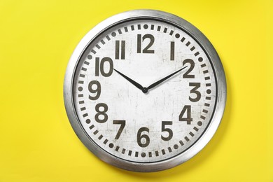 Modern clock on yellow background, top view