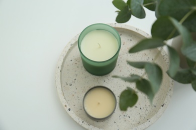 Candles and eucalyptus branches on white table, above view. Interior element