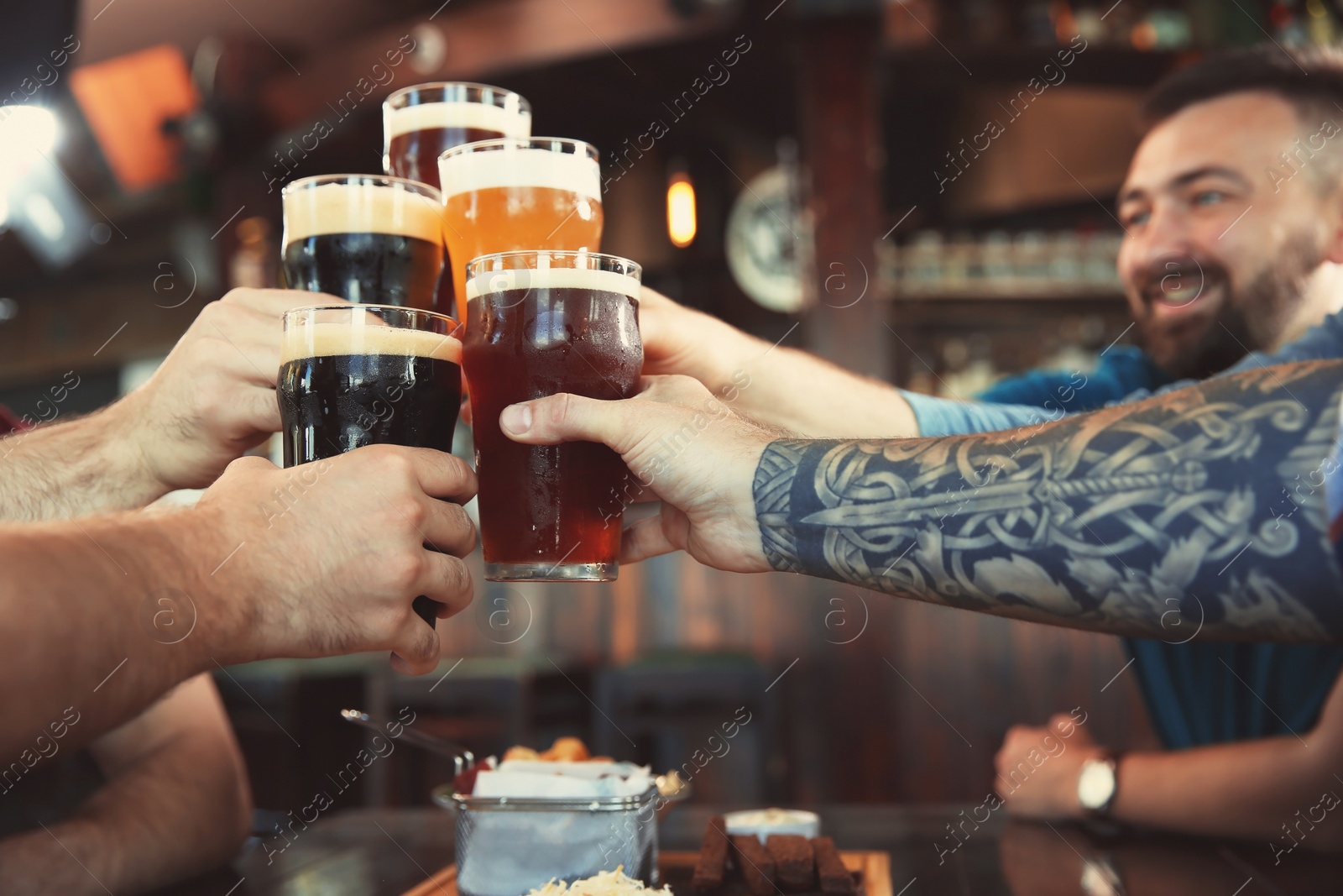 Photo of Friends clinking glasses with beer in pub