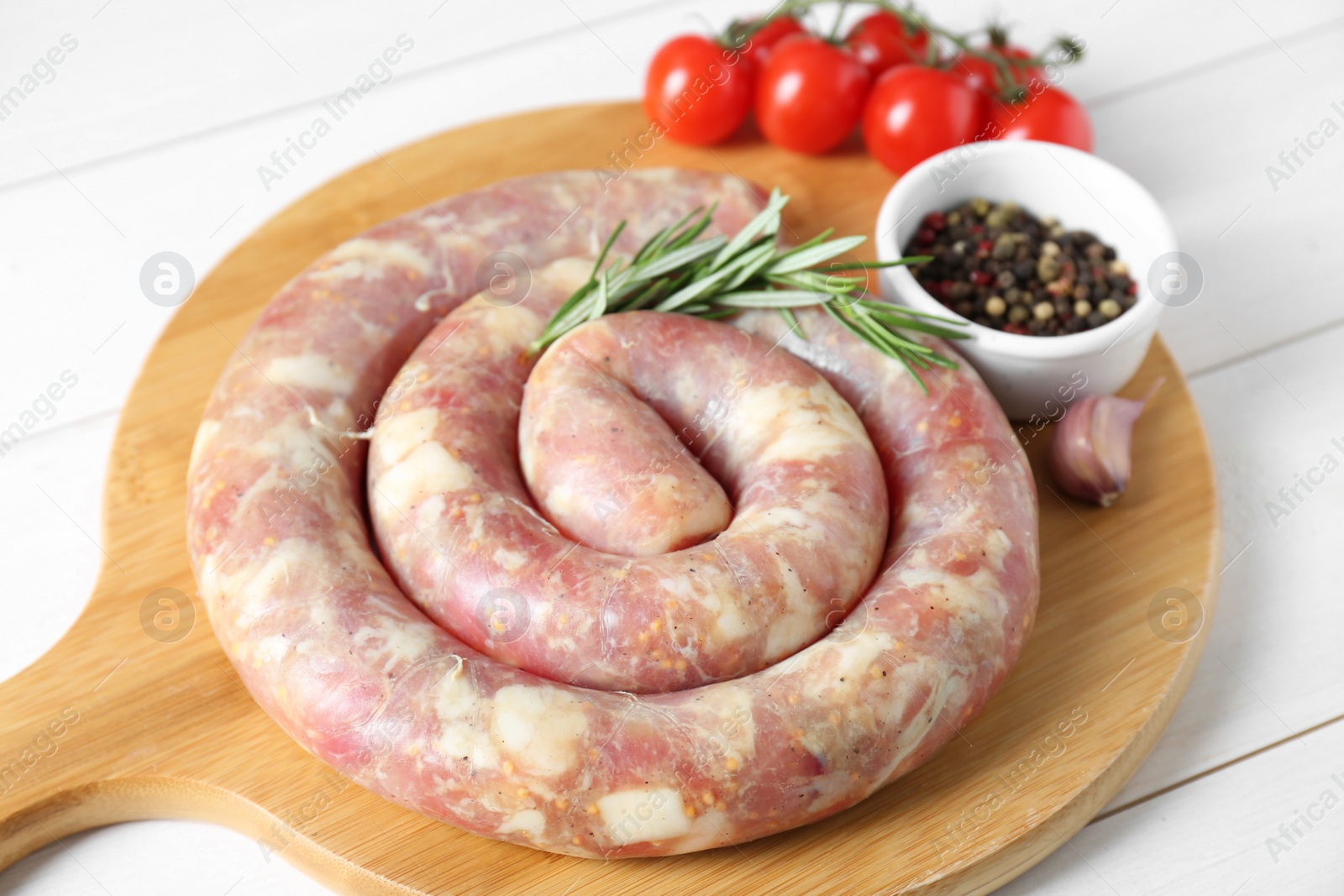 Photo of Raw homemade sausage, rosemary, garlic and peppercorns on white wooden table, closeup