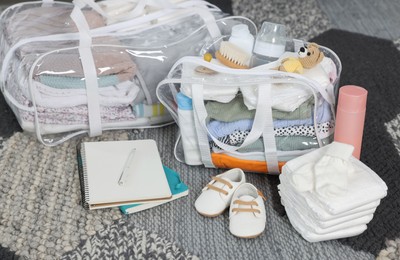 Photo of Packed bags for maternity hospital, notebooks and baby stuff on carpet