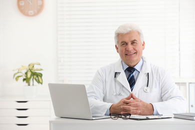 Portrait of senior doctor in white coat at workplace