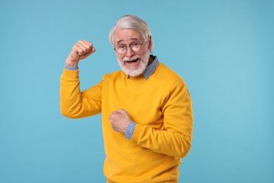 Portrait of stylish grandpa with glasses on light blue background