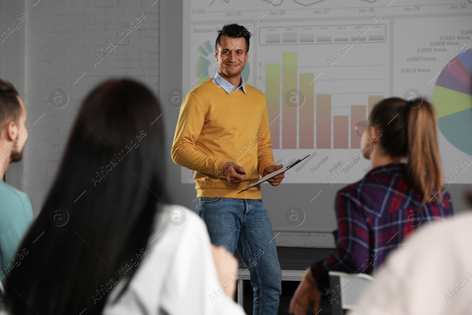 Photo of Male business trainer giving lecture in conference room with projection screen