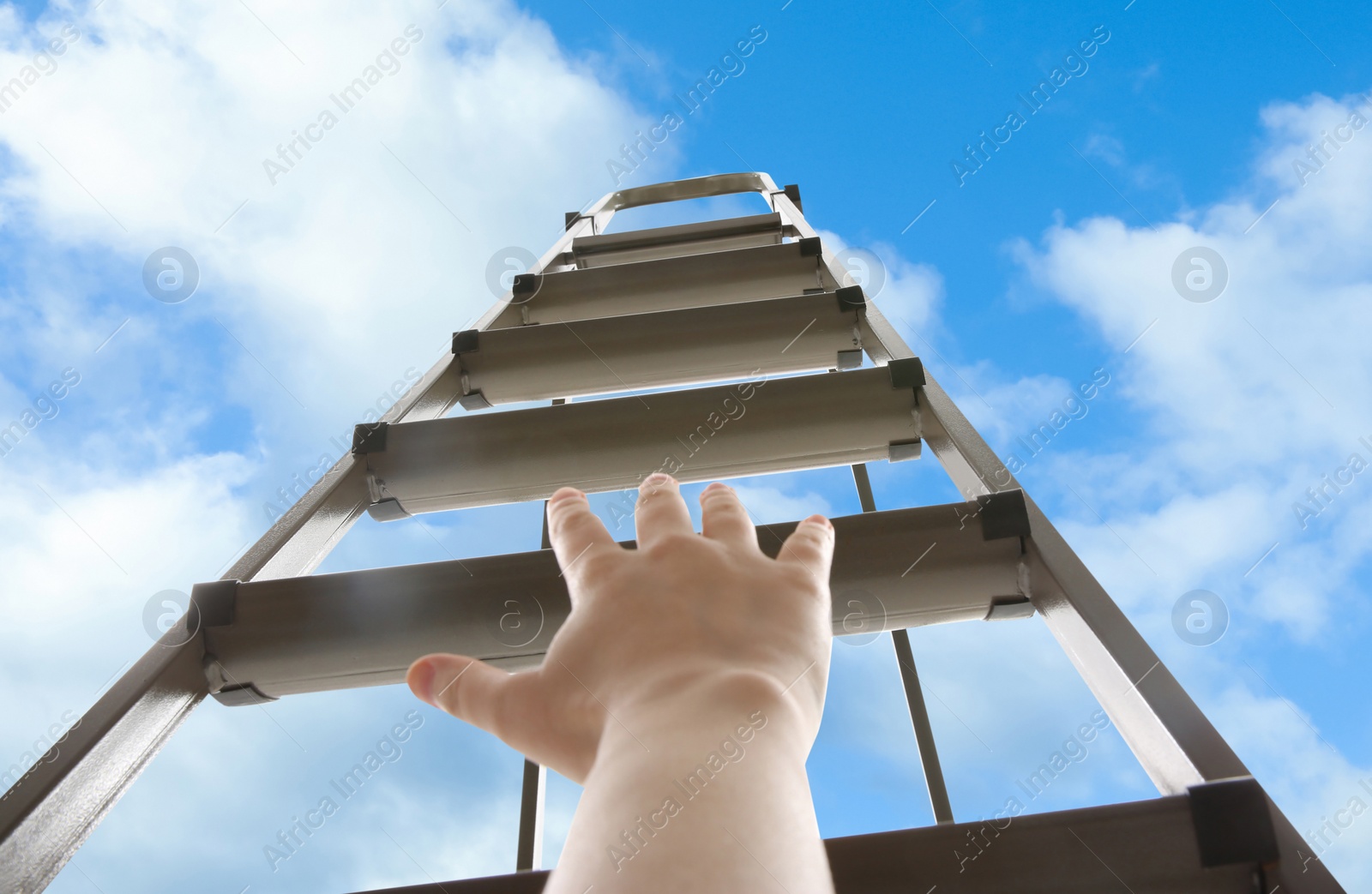 Image of Woman climbing up stepladder against blue sky with clouds, closeup