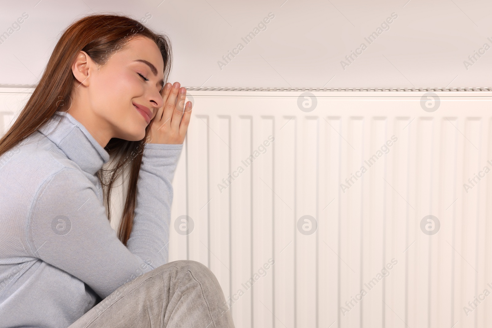 Photo of Woman near heating radiator indoors, space for text