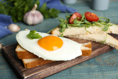 Photo of Tasty fried egg with bread on wooden board, closeup