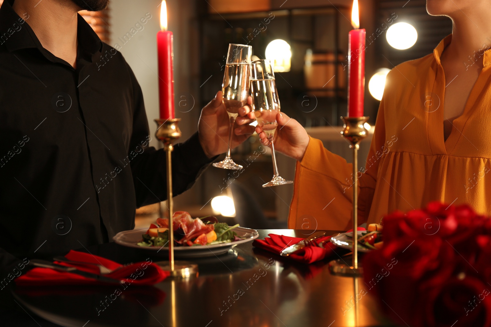 Photo of Couple clinking glasses of champagne at romantic dinner in restaurant, closeup