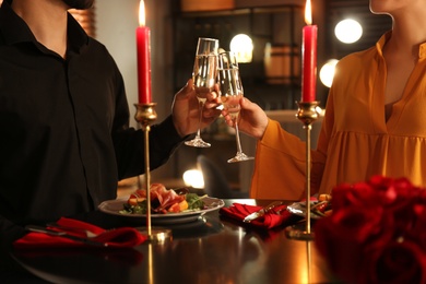 Photo of Couple clinking glasses of champagne at romantic dinner in restaurant, closeup