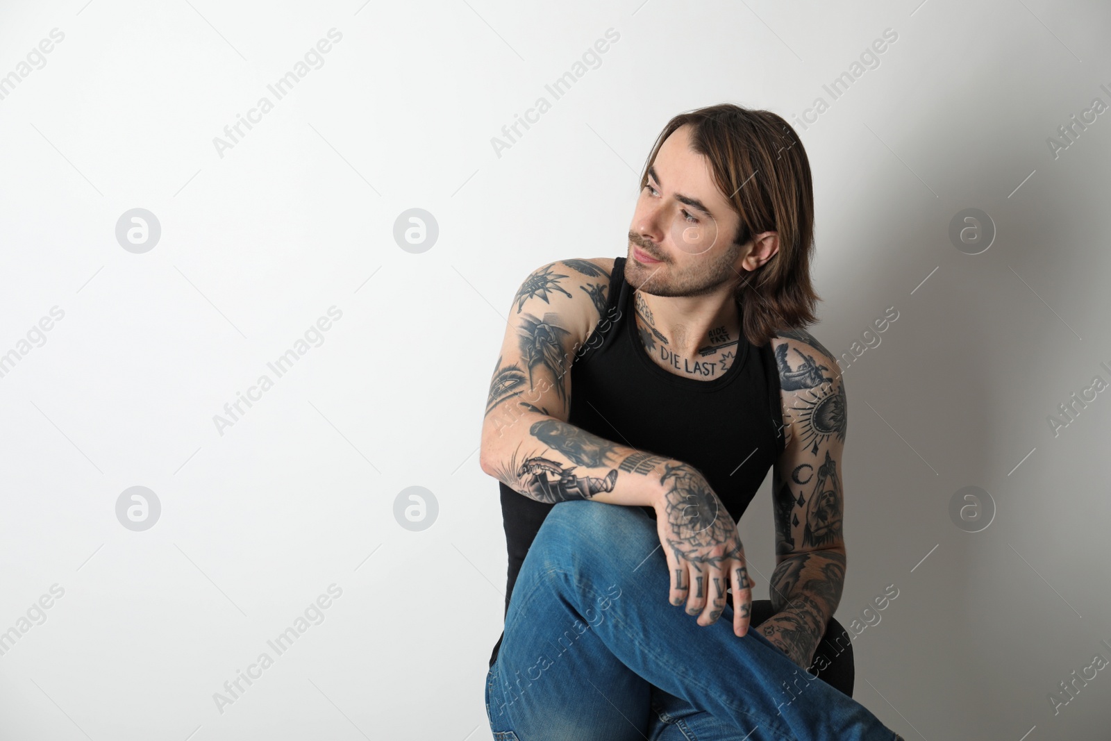 Photo of Young man with tattoos on body against white background