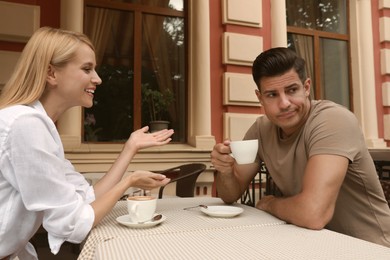 Photo of Man having boring date with talkative woman in outdoor cafe