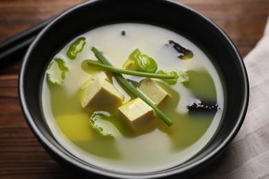 Photo of Bowl of delicious miso soup with tofu served on wooden table, closeup