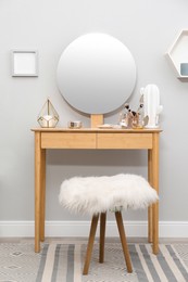 Photo of Stylish room interior with wooden dressing table and mirror on light wall