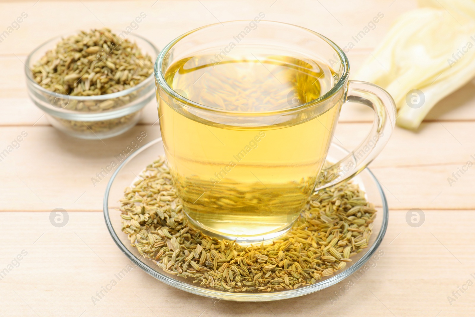 Photo of Aromatic fennel tea, seeds and fresh vegetable on wooden table, closeup