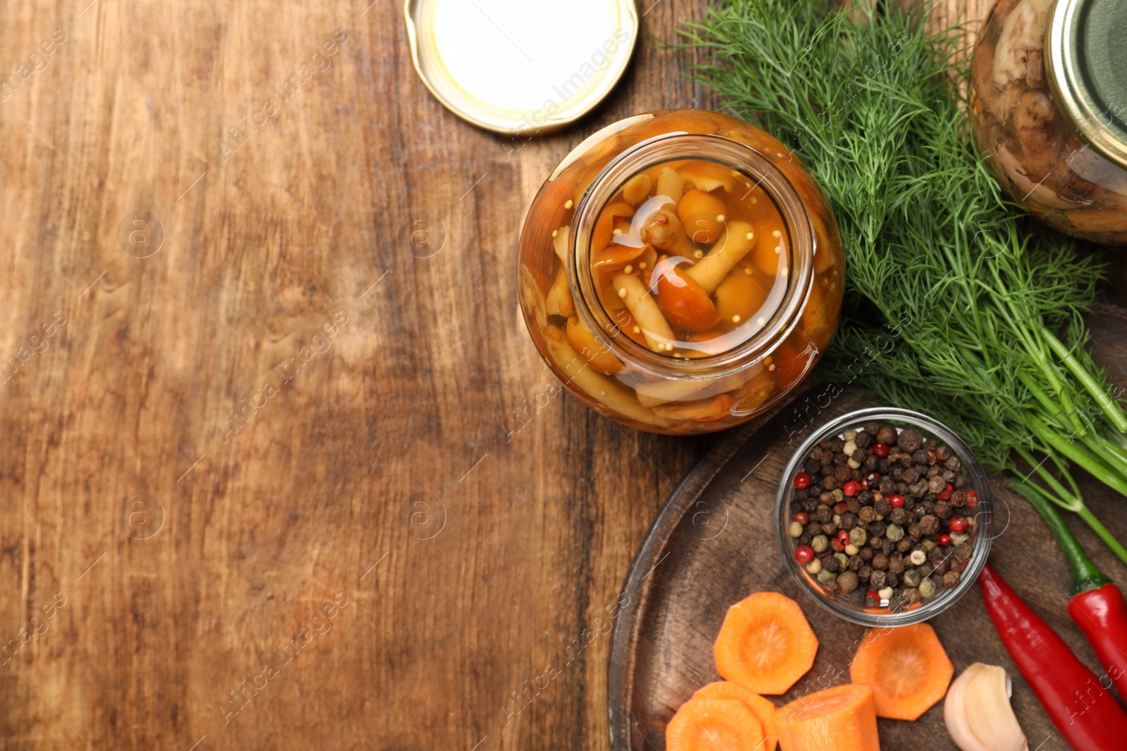 Photo of Delicious marinated mushrooms in glass jar on wooden table, flat lay. Space for text