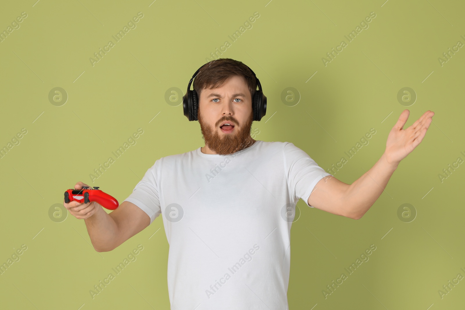 Photo of Confused man with game controller on pale green background