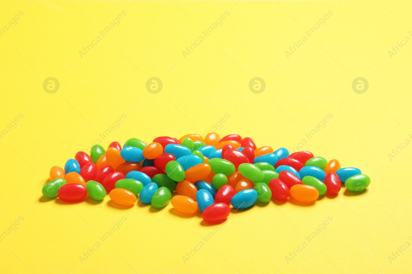 Photo of Delicious bright jelly beans on color background